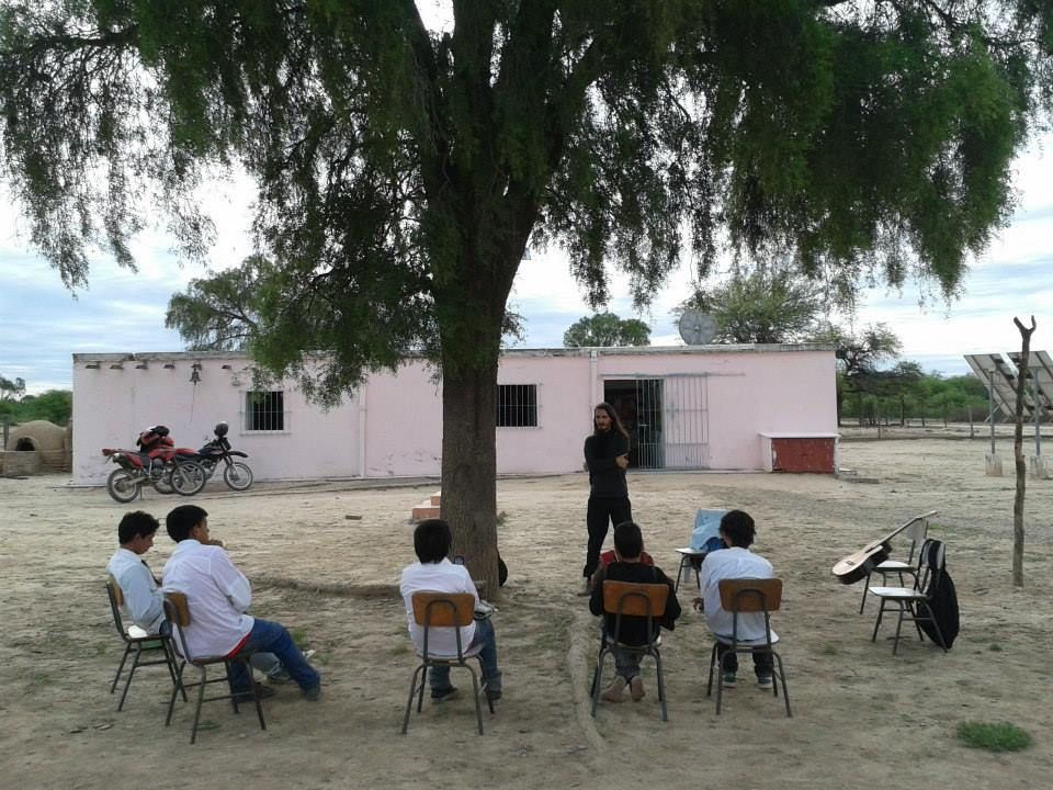 Alunos sentados em roda no pátio de terra de uma escola rural